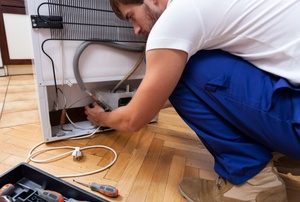 A repair man fixing a refrigerator.