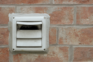 dryer vent outside mounted to a brick wall