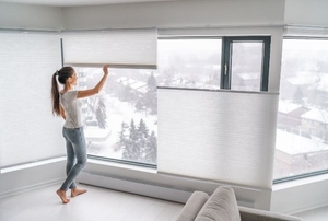 Women adjusting blinds on large window