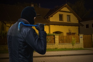 A burglar looks at a house.