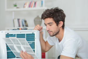 man looking a piece off the back of an air conditioner