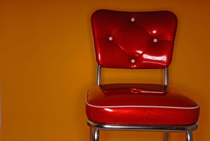 A red vinyl chair against an orange wall.