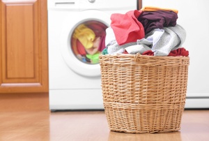 A hamper next to a washing machine.
