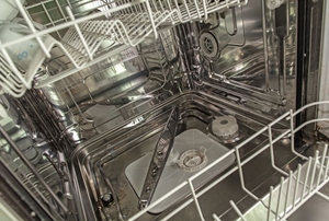 With the dishwasher open and the bottom rack pulled out, the lower dishwater spray arm can be seen.