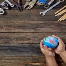 hands holding a globe surrounded by tools