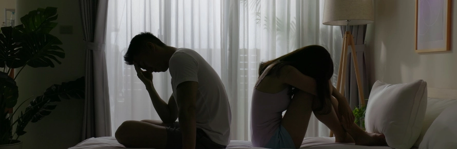 Photograph of a frustrated looking couple in a bedroom 