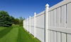 New and contemporary white vinyl fence running across a nicely landscaped backyard with lawn and blue sky.
