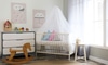 Baby nursery with canopy over the crib, a wooden rocking horse, and a dresser.
