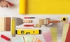 painting supplies and a hand spreading yellow paint with a roller