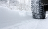 A close-up image of a car driving in snow with snow tires on.