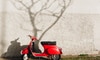 a red scooter against an off-white wall