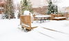 A snow-covered backyard and deck. 