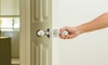A hand grasping a doorknob on a white door. 
