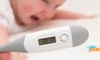 closeup of a thermometer with a baby in the background