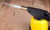 A yellow soldering torch with a flame. 