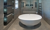 A white oval shaped bath tub in an expensive new home in an ultra modern bathroom.