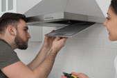 couple installing kitchen stove hood vent fan