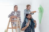 A family painting a white room green.