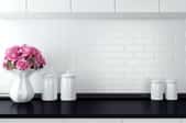 A black kitchen counter with a white backsplash and accessories. 