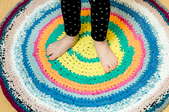 Person standing on a round fabric rug