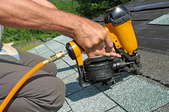 Carpenter uses nail gun on a roofing job.