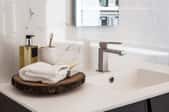 A sleek modern bathroom with a hand towel and soap on a vanity.