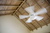 a wooden ceiling peak with white ceiling fan in motion