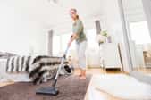 A woman uses a vacuum.