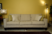 a tan sofa against a yellow wall with lamps on both sides of it.
