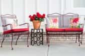 Metal patio furniture with red cushions.