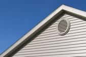 An oval soffit vent on the side of a roof.