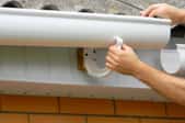 A woman installs gutters.