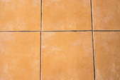 A beige tile floor with old, stained grout.