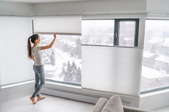 Women adjusting blinds on large window