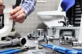 a bathroom with plumbing tools on the floor and a person fixing a sink pipe