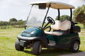 A golf cart parked on the green of a golf course.