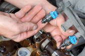 hand holding a fuel injector in an engine