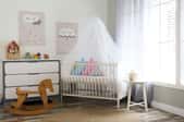 Baby nursery with canopy over the crib, a wooden rocking horse, and a dresser.