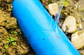 A cracked, leaking blue water pipe.