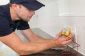 a man checking the voltage on an outlet with a multimeter