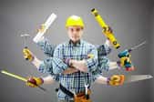 A handyman with many arms coming off of him holding tools. 
