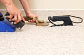 A carpet installer fixes the seam of a carpet using a carpet iron.