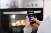 Someone using a smart phone to turn their oven on. 