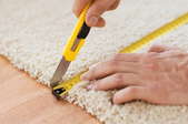 someone measuring and cutting carpet