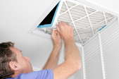 man adjusting filter in large air vent