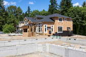 Neighborhood construction with house foundation in the foreground and partially finished house in the background. 