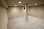 finished basement with carpeting floor and beige walls.