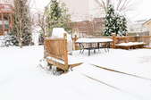 A snow-covered backyard and deck. 
