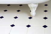 Vintage-style, checkered tile floor in a bathroom, beneath a claw foot tub.