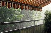 Rain pours off of an attached awning covering a deck.